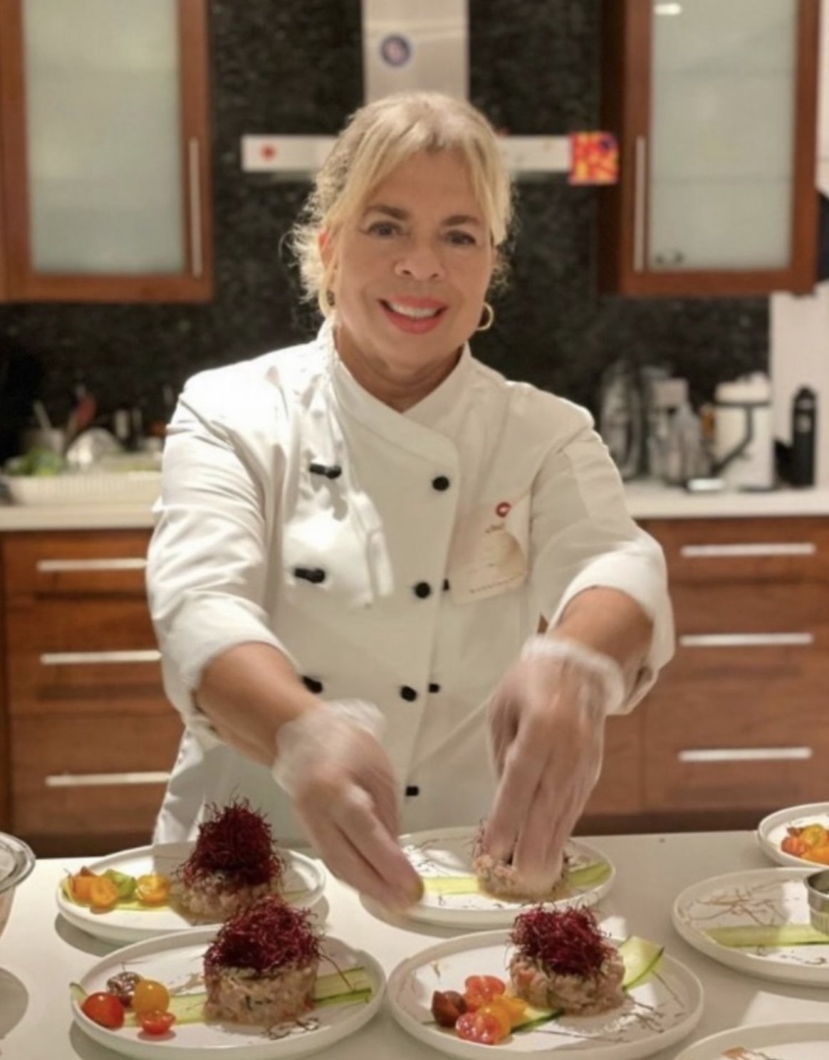 Chef Reni carefully finishing plated dishes in the kitchen